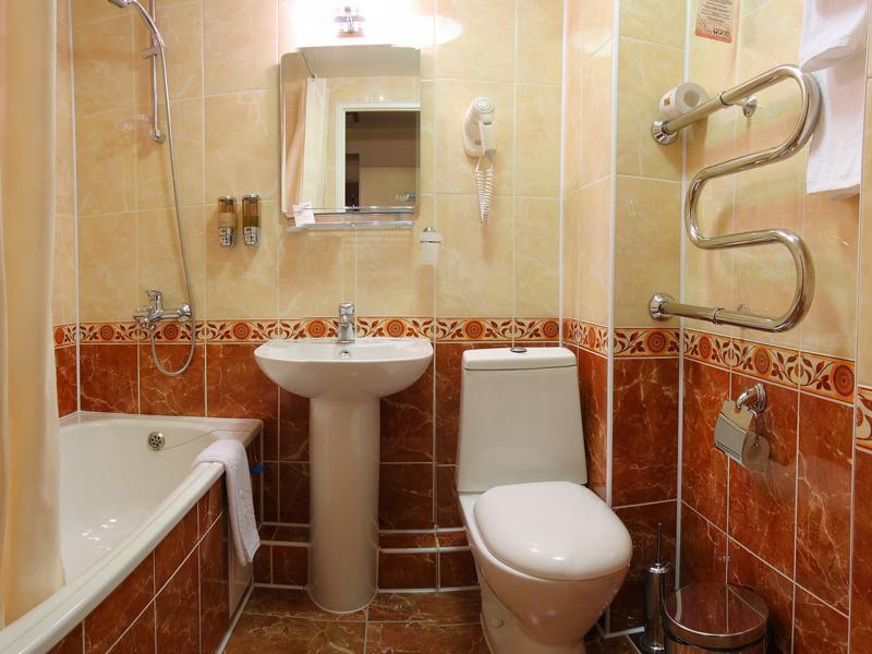 Маленькая ванная комната с белой сантехникой и полотенцами